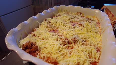 mozzarella cheese being added and sprinkled into lasagne dish by hand