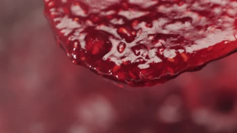 close-up of dripping raspberry jam on a spoon