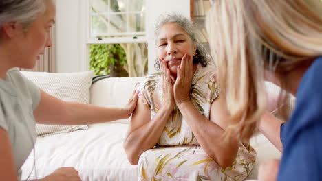 senior biracial woman is sad and comforted by friends at home