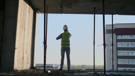 Engineer-Builder-on-the-roof-of-the-building-at-sunset-stands-in-VR-glasses-and-moves-his-hands-using-the-interface-of-the-future.-Futuristic-engineer-of-the-future.-The-view-from-the-back