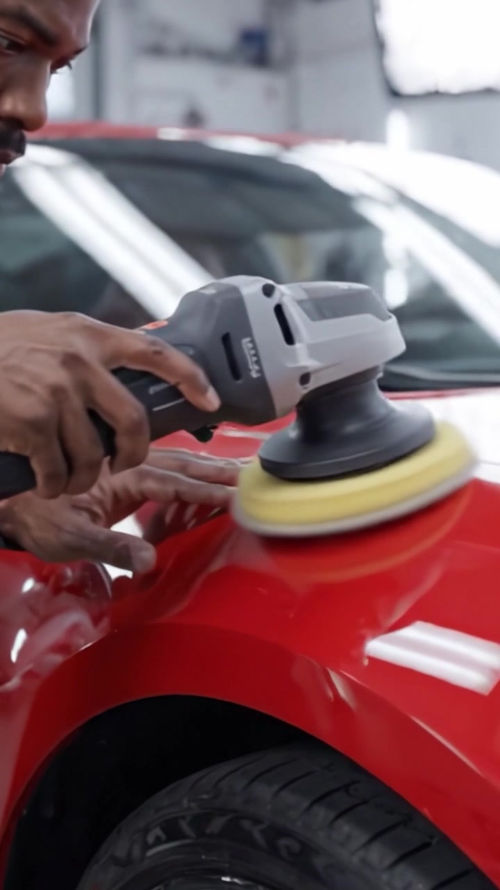 Professional Car Detailing: A Skilled Technician Polishing a Shine on a Vibrant Red Vehicle to Achieve a Flawless Finish and Showcase its Gleaming Surface