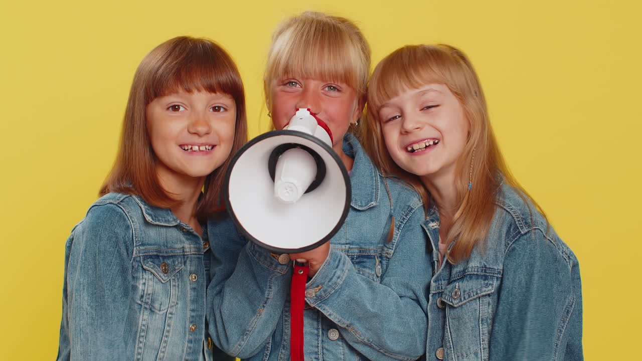 Three girls friends scream shout in megaphone proclaiming news loudly announcing advertisement