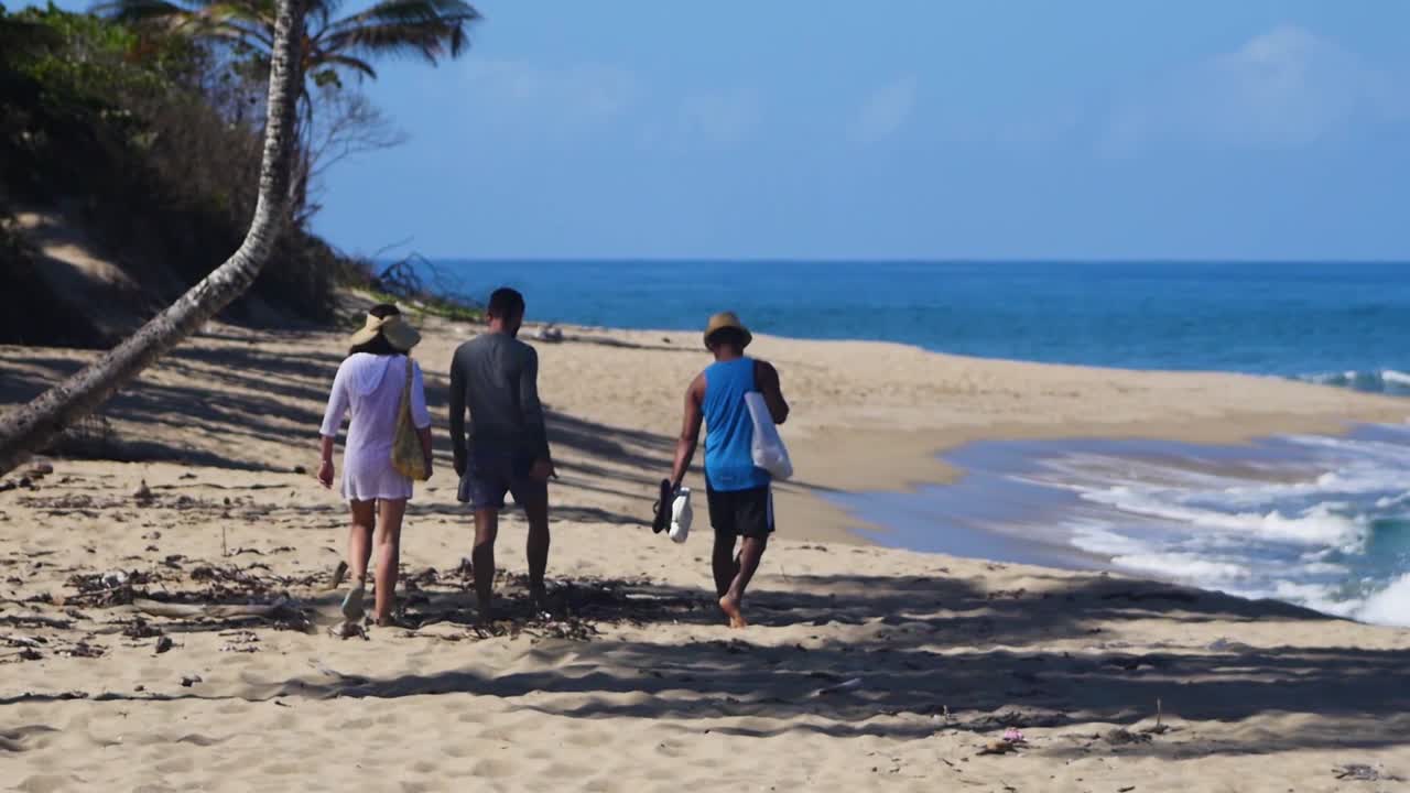 A group of friends walking along the shore of the beach.