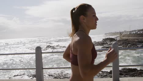 Sporty-Caucasian-woman-exercising-on-a-promenade-on-seaside