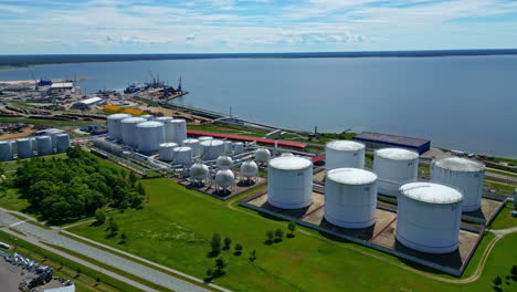 Slow-motion-drone-flight-over-an-oil-tank-area,-industry-on-the-water-of-Estonia-on-a-sunny-day,-copy-space