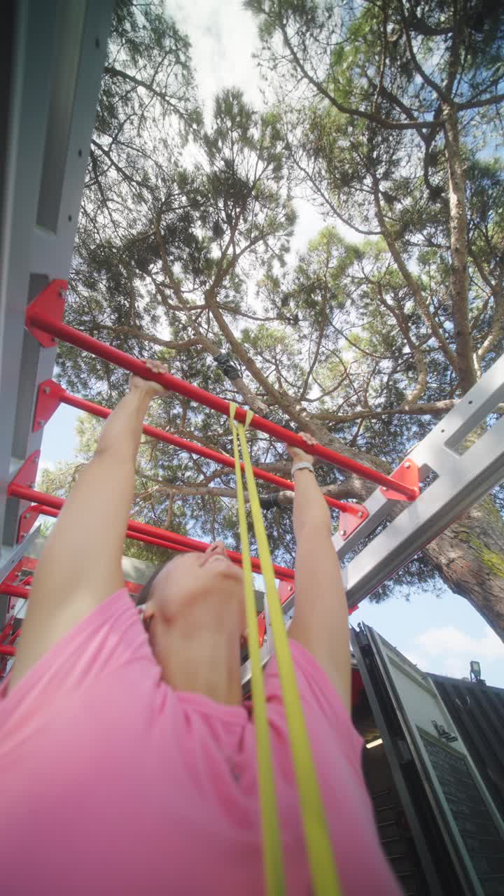 Woman doing pull-ups with a resistance band at an outdoor gym