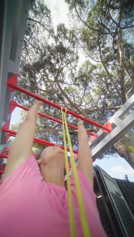 woman doing pull-ups with a resistance band at an outdoor gym