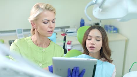 Female-dentist-using-tablet-computer.-Dentist-showing-patient-treatment-plan