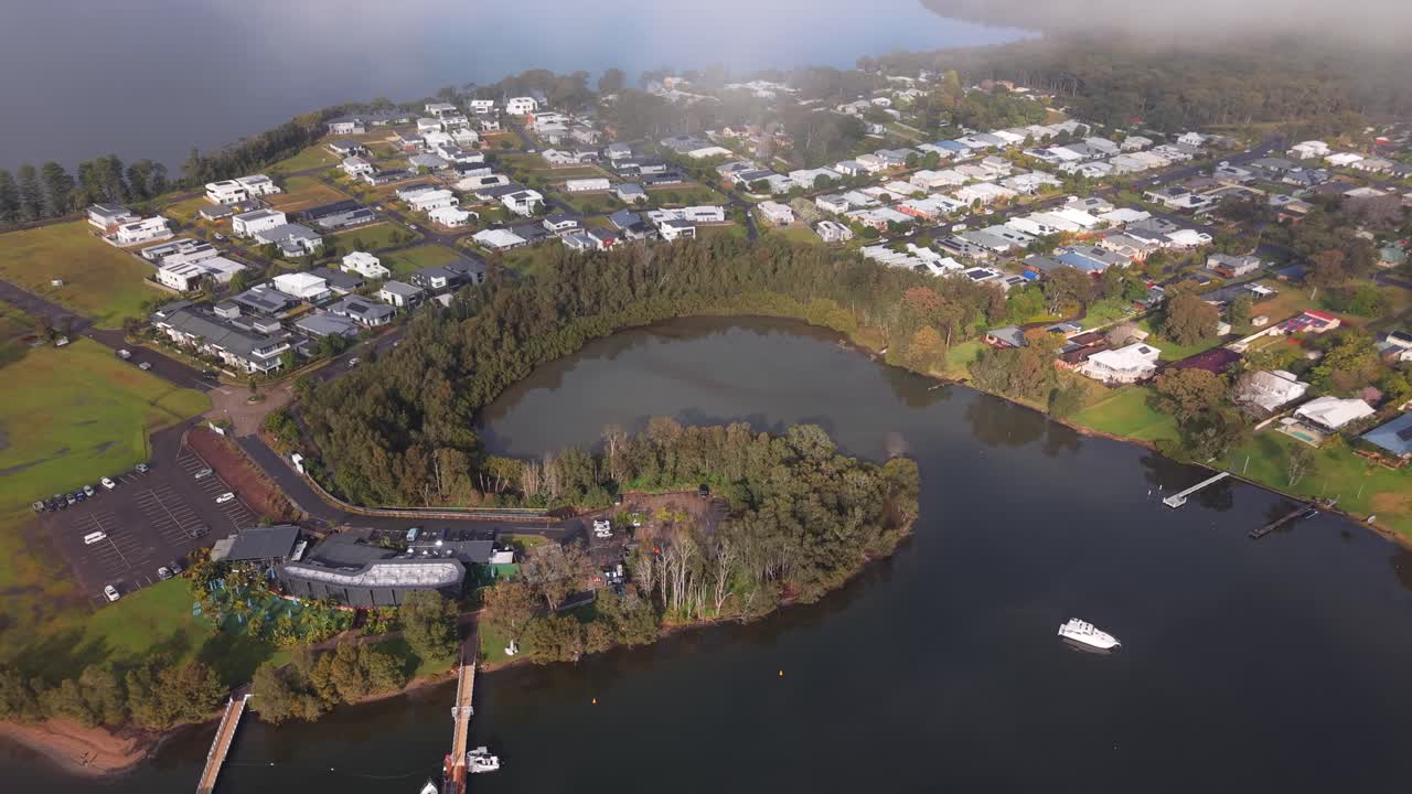 Trinity Point aerial overview of waterfront homes, marina, and surrounding coastline through clouds