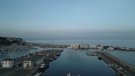 Vista-Panorámica-Aérea-Del-Muelle-Del-Puerto-De-Arenys-De-Mar-En-Cataluña-Barcelona,-Costa-Azul,-Agua-De-Mar-Y-Horizonte,-Establecimiento-De-Tiro