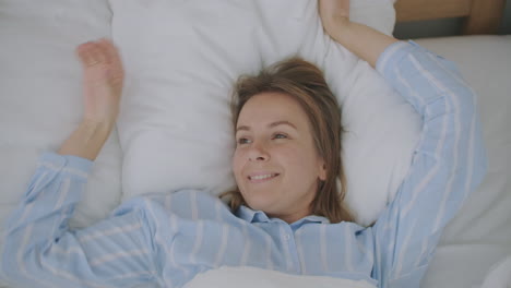 Close-up-face-of-young-Caucasian-woman-lying-and-stretching-on-bed-after-waking-up-early-in-the-morning