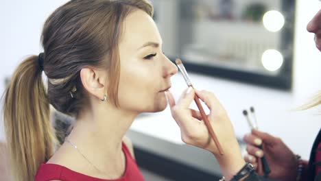 Vista-De-Cerca-Del-Maquillador-Aplicando-Sombra-De-Ojos-En-El-Párpado-Con-Una-Brocha-De-Maquillaje.-Maquillaje-Profesional.-Tiro-En-Cámara-Lenta