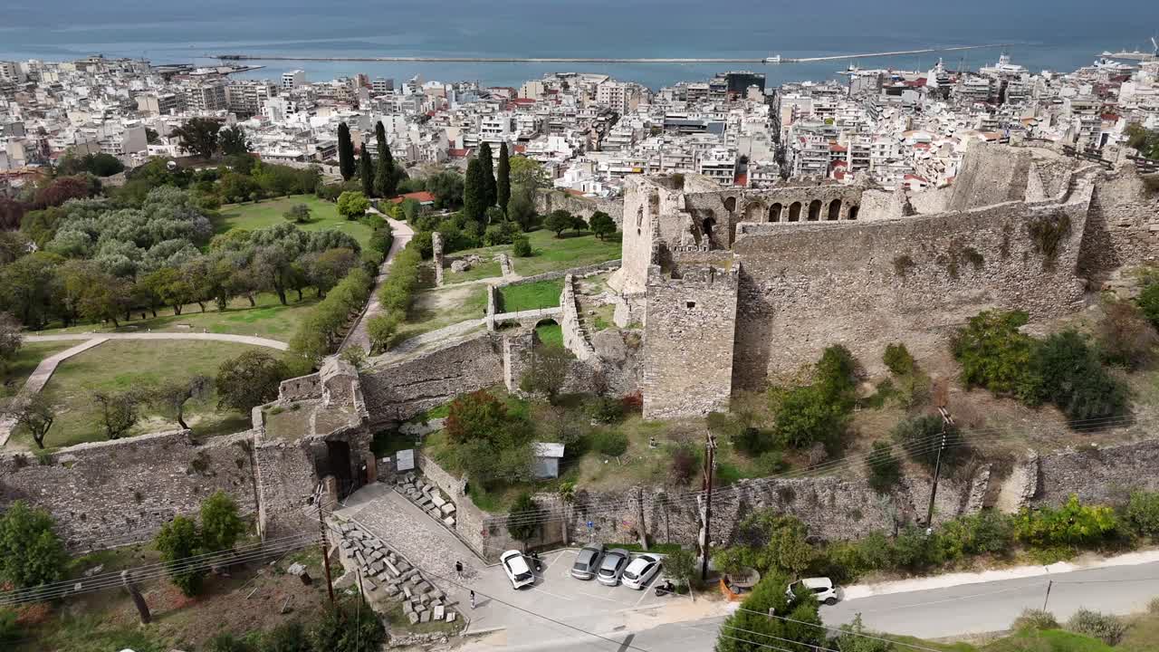 Patras Castle,Aerial forward from Castle's main entrance towards the city and sea on a sunny day. Inside of the castle all green,behind lies the Patras city and sea