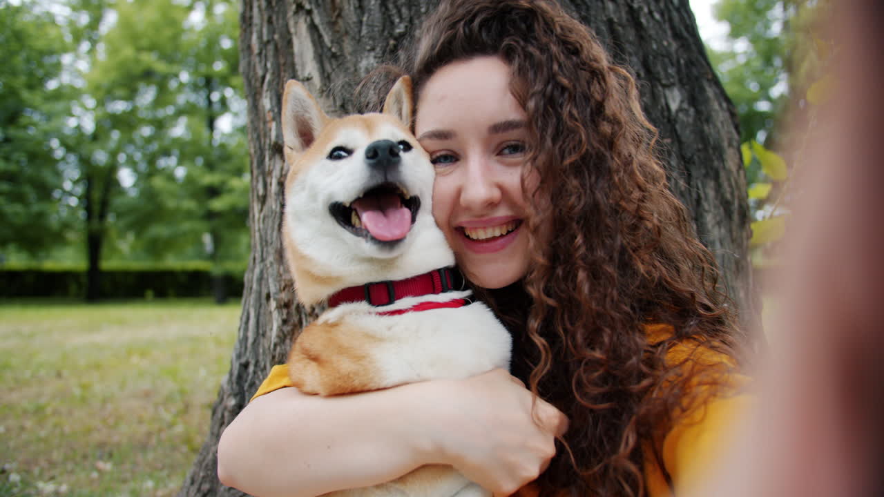 Mujer tomándose una selfie con su perro Shiba Inu en un parque