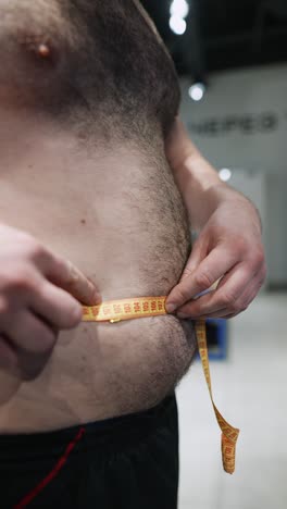 man measuring his waist circumference