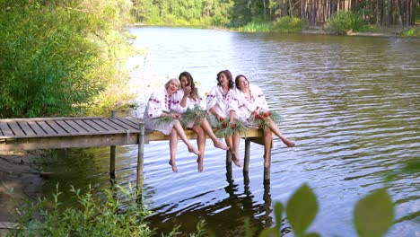 lovely women in traditional ukrainian dresses sing on pontoon bridge over river