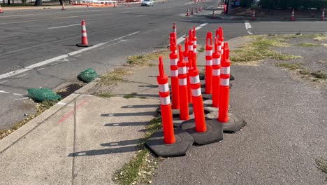 safety cones gathered onto the sidewalk next to an asphalt road