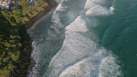 Aerial-views-over-surfers-at-Burleigh-Heads-at-sunrise,-Gold-Coast,-Queensland,-Australia