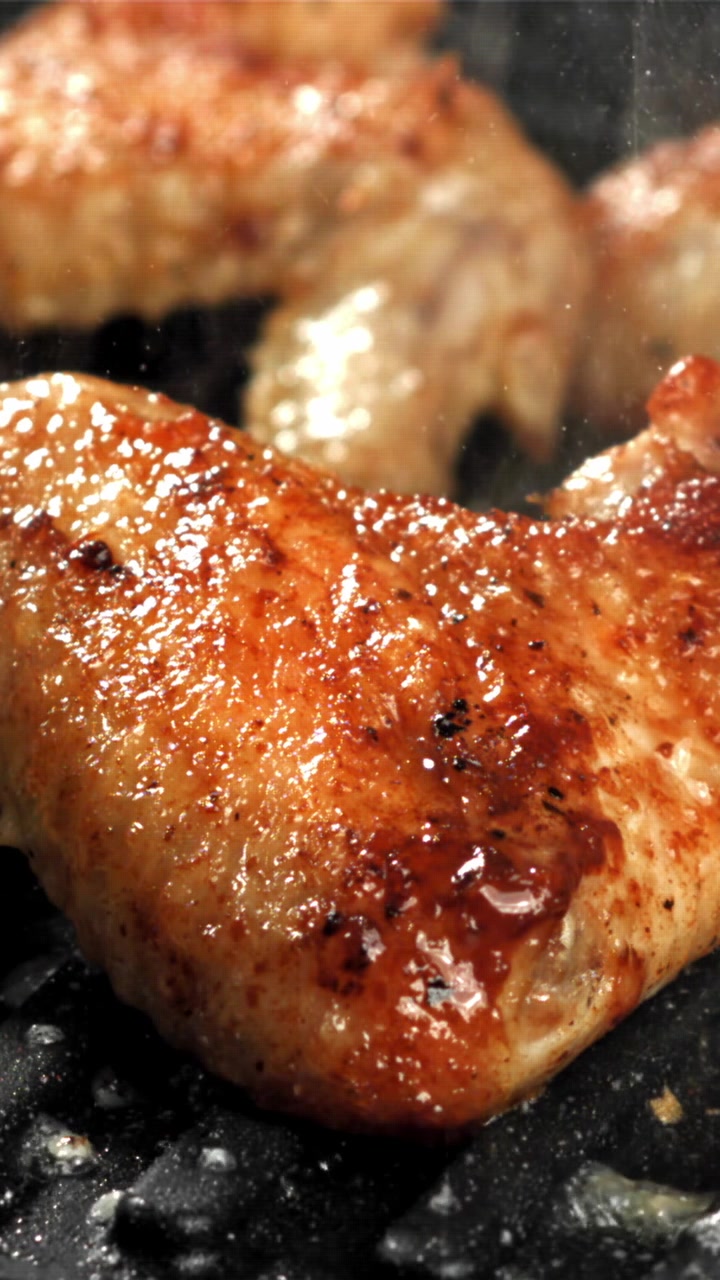 Primo piano di deliziose alette di pollo che sfrigolano su una griglia calda