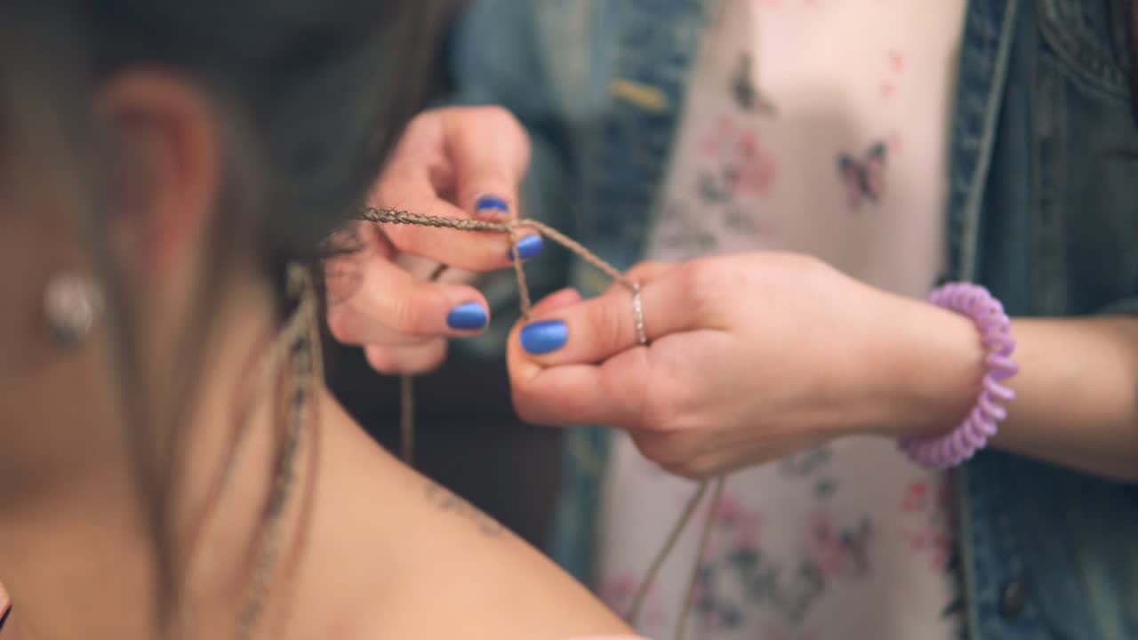 Closeup view of the hairdresser's hands doing dreads for a young woman in the hair salon. Shot in 4k
