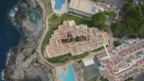 aerial view descending birdseye above mallorca holiday resort on mediterranean coastal cliff edge