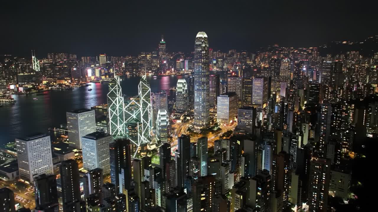 Experience the vibrant city of Hong Kong illuminated at night, revealing its stunning skyline and high-rise buildings along the waterfront. A captivating spectacle of urban life and architecture.