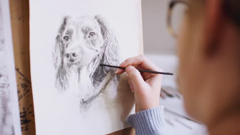 artista adolescente sentada en un caballete dibujando una imagen de un perro de una fotografía en carbón