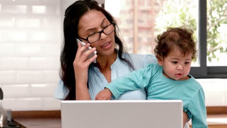 mother using laptop while carrying baby