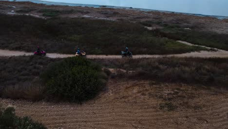 group of people riding atvs on a dirt track through arid landscape