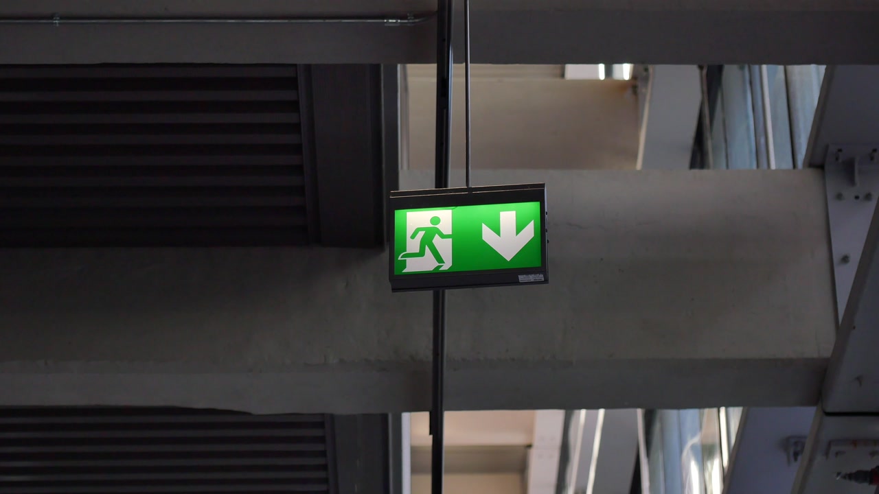 Señal de salida de emergencia verde iluminada con flecha hacia abajo