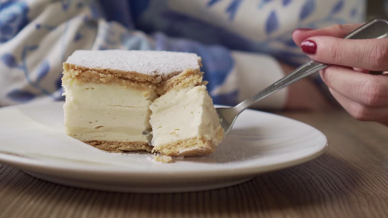 Closeup of cutting out a piece of cake with a fork, shot from side ...