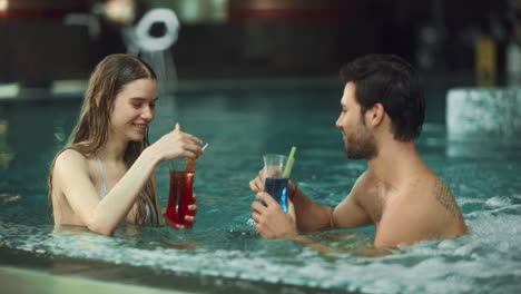 closeup sexy couple relaxing in pool spa. happy man and woman enjoying drinks