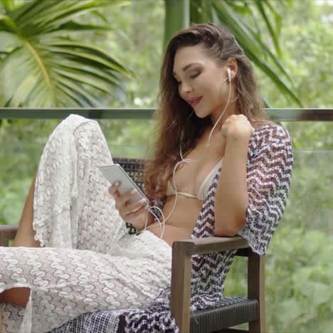 Lady-listening-to-music-and-using-smartphone-on-balcony