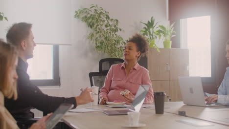 pregnant woman sitting at table talking with a coworker in a meeting room