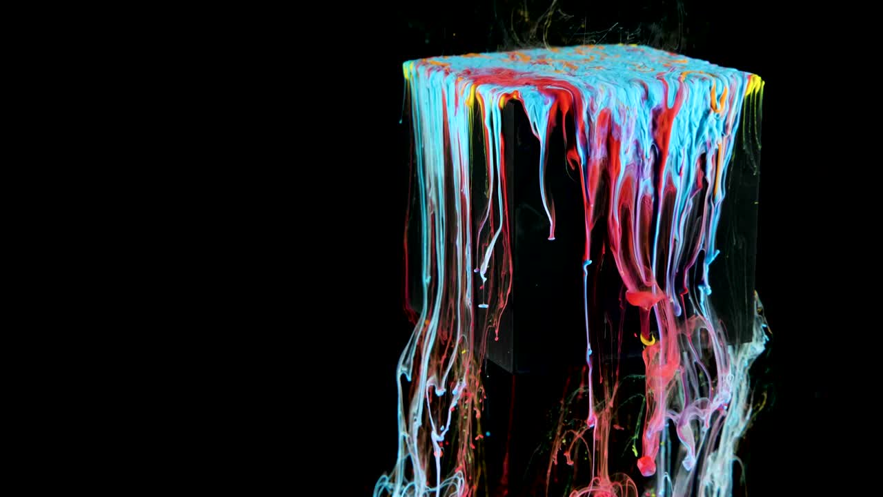 Multicolored ink paint slowly flows from the cube underwater