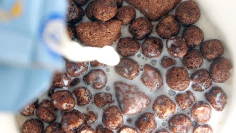vertiendo leche sobre el cereal de chocolate