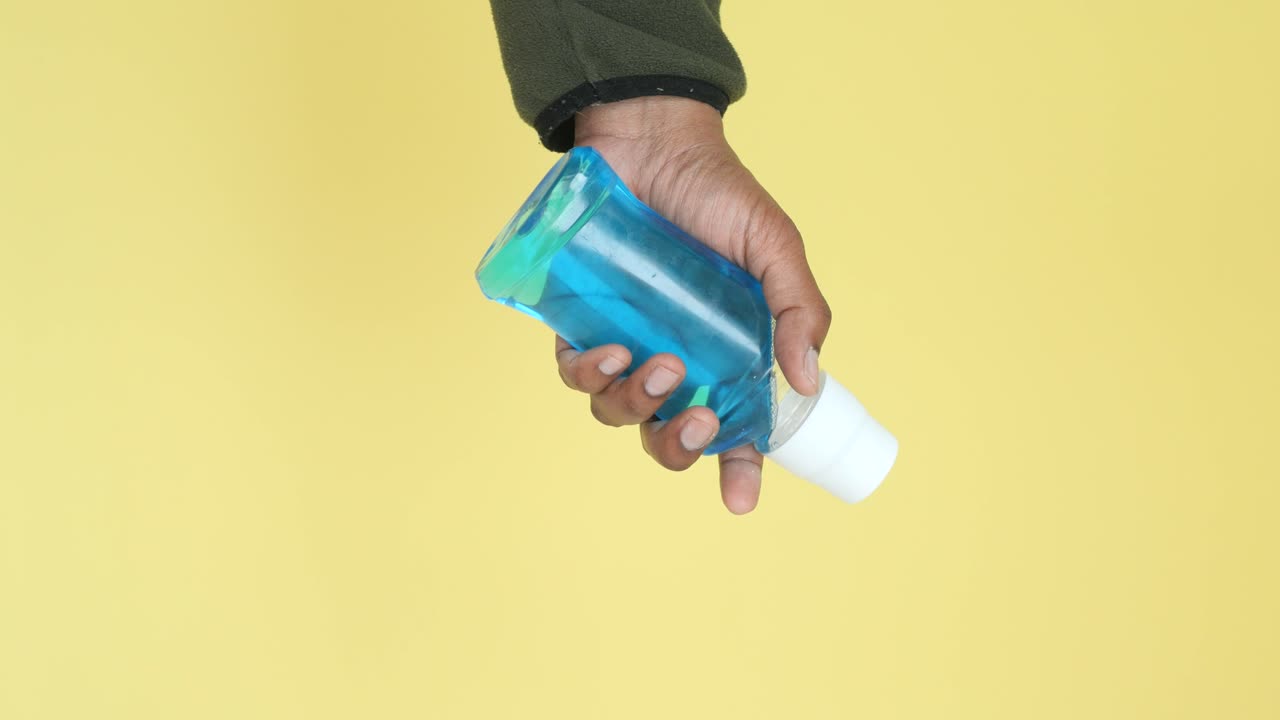 mano con una botella de enjuague bucal