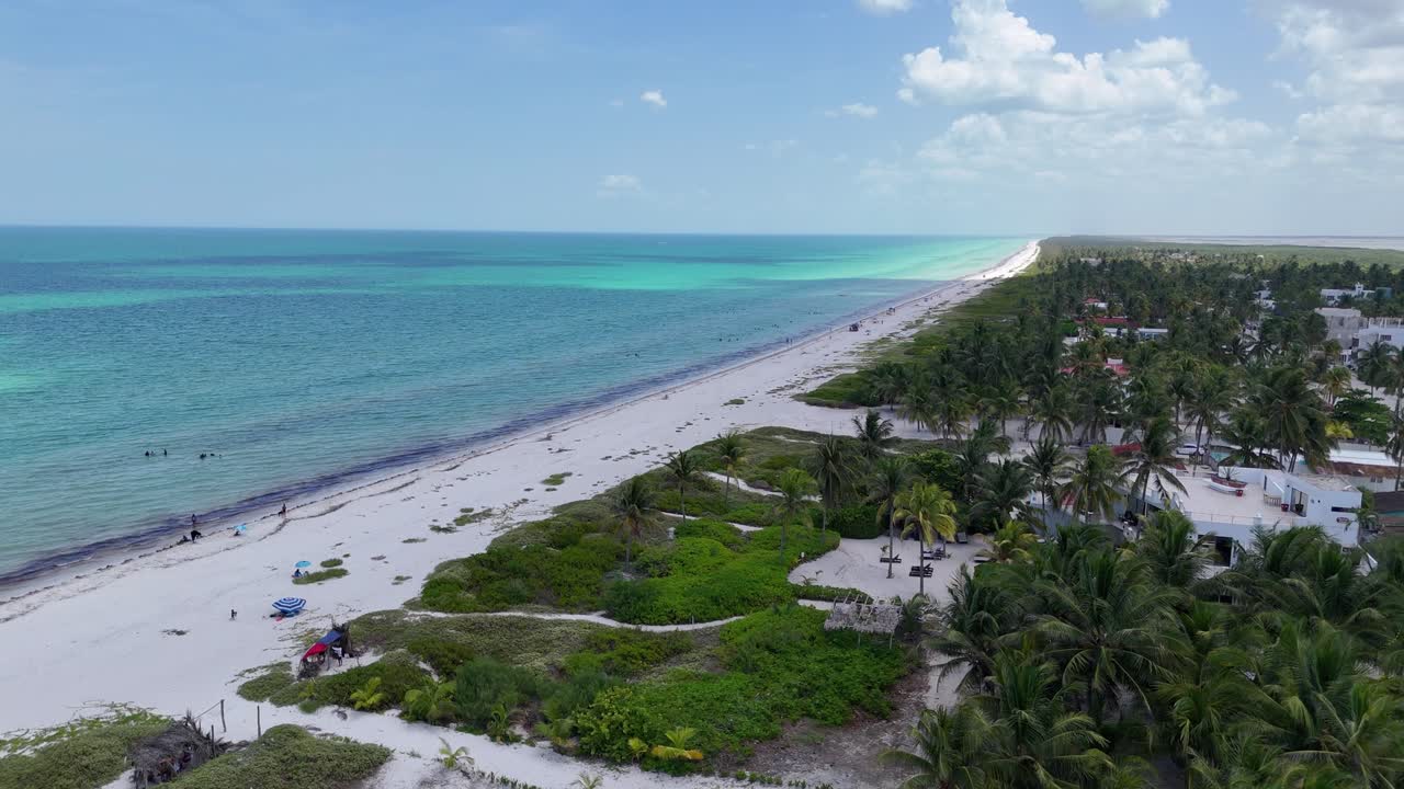 Aerial view of El Cuyo, Yucatán, Mexico. White sandy beach, turquoise Caribbean waters, and palm-lined coastline with small town houses in the background