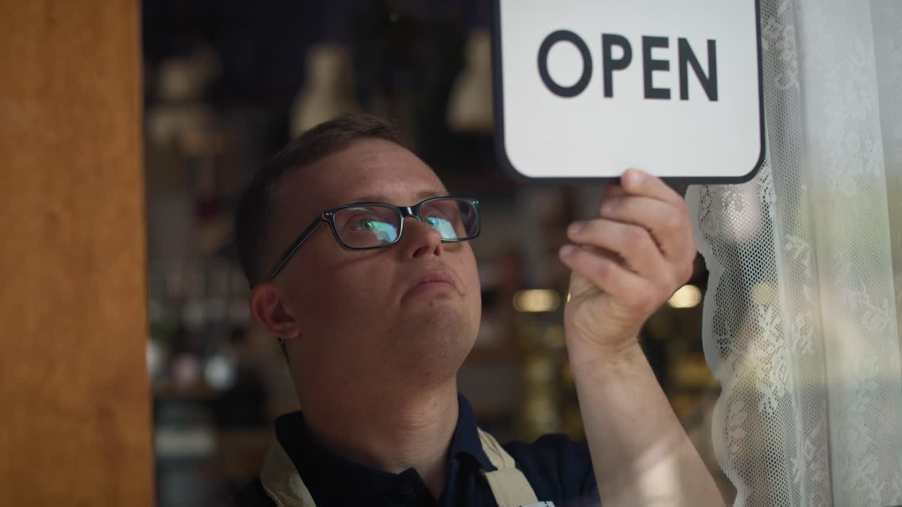Caucasian waitress changing sign on doors from open to closed.