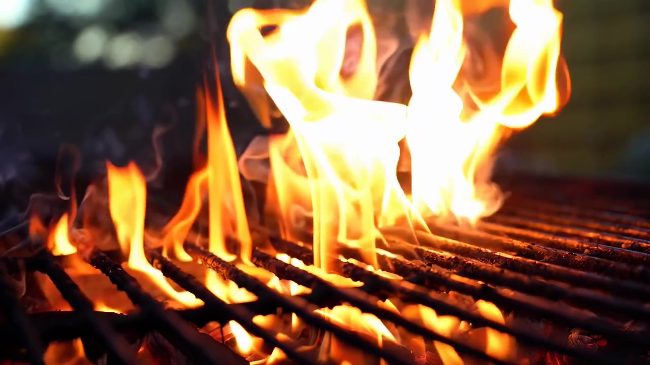 Fiamme vivaci e fumo che si alzano da una griglia per barbecue calda
