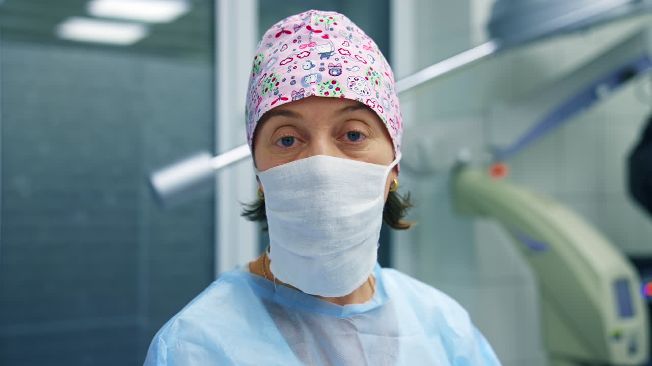 Doctor in scrubs and facial mask tells methods of vision correction to the camera. Modern clinic background.