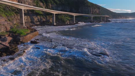 sunrise sea cliff bridge costal drone view iconic famous stanwell park waves ocean crashing south coast nsw australia landscape royal national park wollongong coalcliff iiawarra sydney slow forward