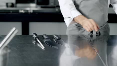 el chef se prepara para cocinar en la cocina. las manos del hombre colocando cuchillos.