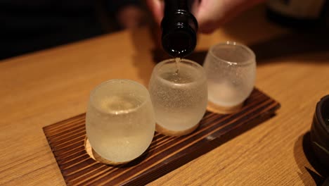 sequence of sake being poured into two glasses