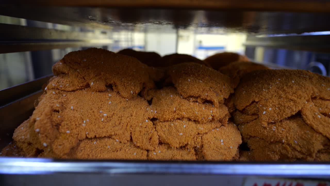 Close up shot of chicken breasts on a shelf that has been coated with flour ready to be fried in a food factory