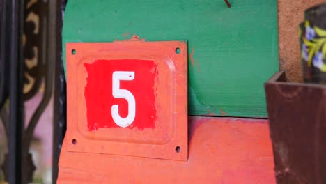 close-up of a weathered red metal sign with the number 5