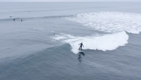 Easy-going-waves-in-freezing-waters-of-iceland-with-surfers,-aerial