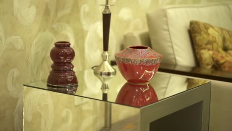 exquisitos adornos elegantemente exhibidos en una mesa de vidrio en el ambiente sofisticado de un salón de hotel