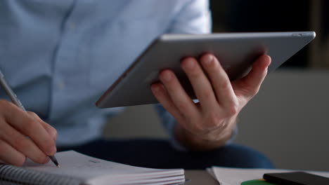 entrepreneur man using tablet writing notebook information research in workplace