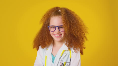 studio portrait of girl dressed as doctor or surgeon with stethoscope against yellow background